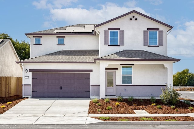 view of front facade featuring concrete driveway, stucco siding, fence, roof mounted solar panels, and a shingled roof