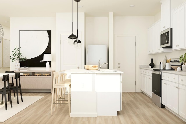 kitchen featuring a center island with sink, pendant lighting, light wood finished floors, white cabinets, and appliances with stainless steel finishes