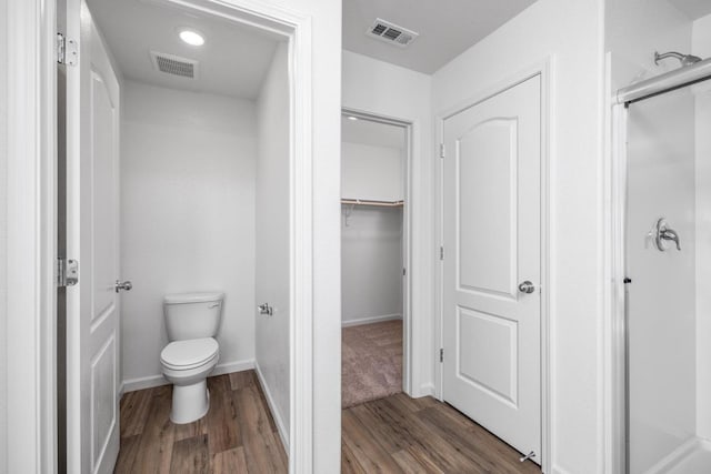 bathroom featuring visible vents, a stall shower, toilet, and wood finished floors