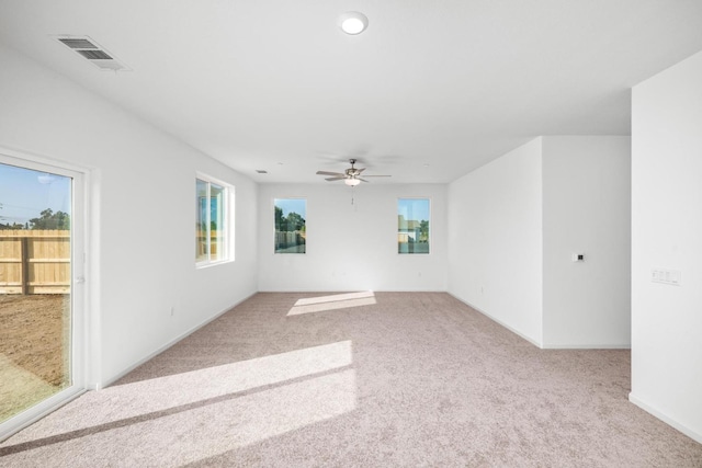 carpeted empty room featuring baseboards, visible vents, a ceiling fan, and a healthy amount of sunlight