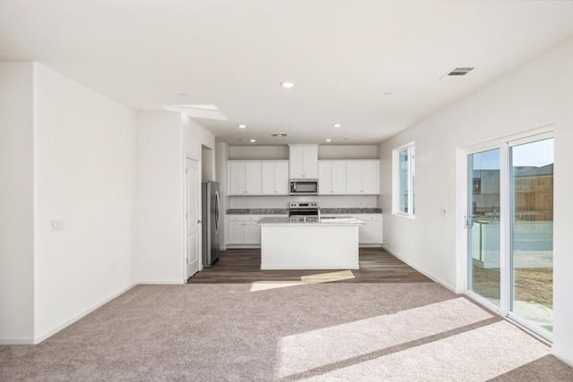 kitchen with visible vents, appliances with stainless steel finishes, white cabinetry, open floor plan, and carpet floors