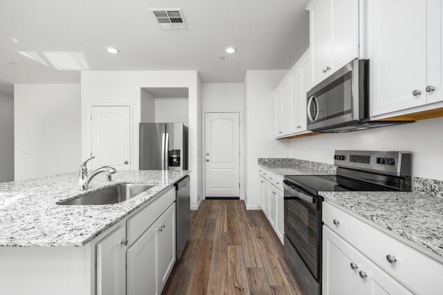 kitchen featuring stainless steel appliances, a sink, dark wood-style floors, visible vents, and white cabinets