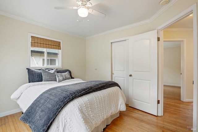 bedroom featuring a closet, light wood finished floors, baseboards, and crown molding