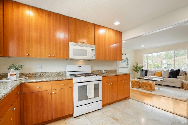 kitchen featuring open floor plan, white appliances, brown cabinetry, recessed lighting, and light stone counters