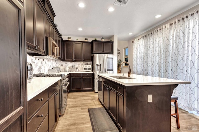 kitchen featuring premium appliances, a breakfast bar, visible vents, a sink, and dark brown cabinetry