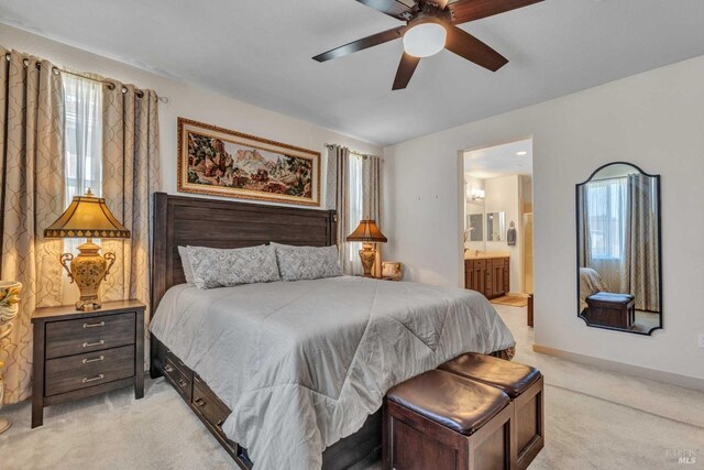 bedroom with ensuite bath, light carpet, and a ceiling fan