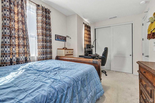 bedroom with visible vents, a closet, and light colored carpet