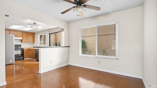 kitchen with light wood-style flooring, black electric range oven, under cabinet range hood, freestanding refrigerator, and dishwasher