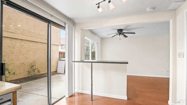 interior space featuring baseboards, wood finished floors, ceiling fan, and rail lighting