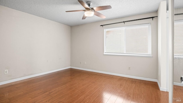 empty room featuring baseboards, a textured ceiling, a ceiling fan, and wood finished floors