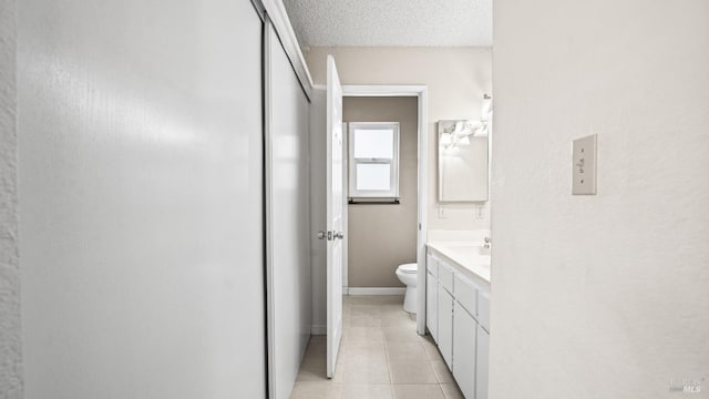 bathroom with baseboards, toilet, vanity, tile patterned floors, and a textured ceiling