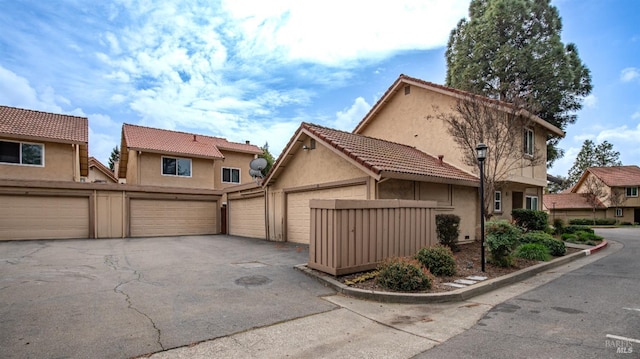 view of front of home with aphalt driveway, stucco siding, a tiled roof, and a garage