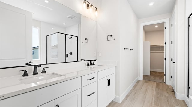 2514 Wisteria Dr, Lodi, CA 95242 - bathroom with a stall shower, double vanity, wood finished floors, a spacious closet, and recessed lighting
