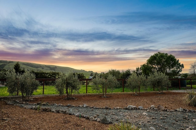 yard at dusk featuring a mountain view and fence