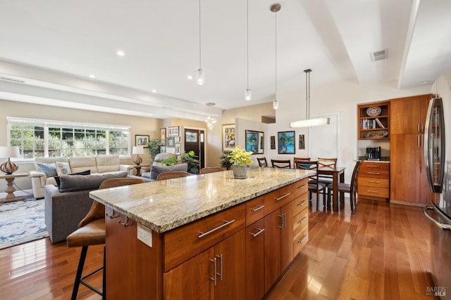 kitchen with open shelves, wood-type flooring, brown cabinets, and stainless steel refrigerator
