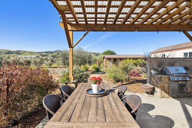 view of patio / terrace featuring an outdoor kitchen, outdoor dining area, a mountain view, and a grill