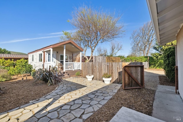 view of patio featuring a porch, a gate, and fence