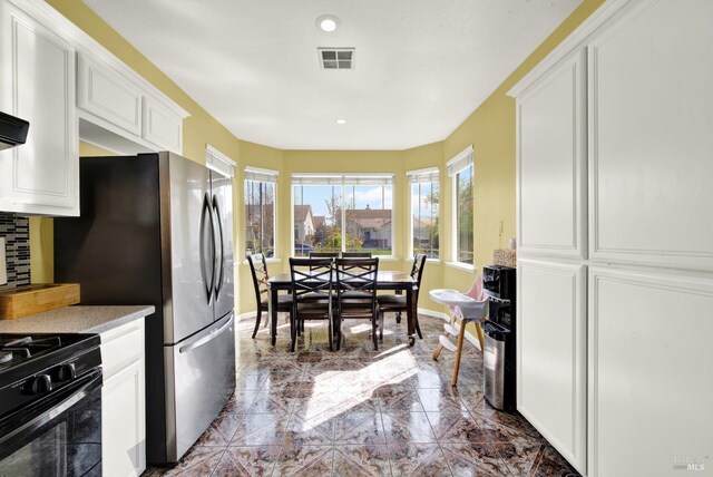 kitchen with white cabinets, backsplash, light countertops, visible vents, and baseboards