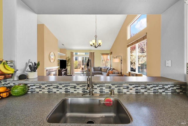 kitchen featuring vaulted ceiling, a sink, open floor plan, an inviting chandelier, and pendant lighting