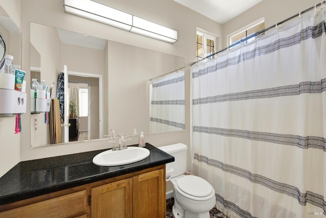 bathroom with a shower with shower curtain, a healthy amount of sunlight, toilet, and vanity