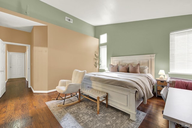 bedroom with vaulted ceiling, visible vents, baseboards, and wood finished floors