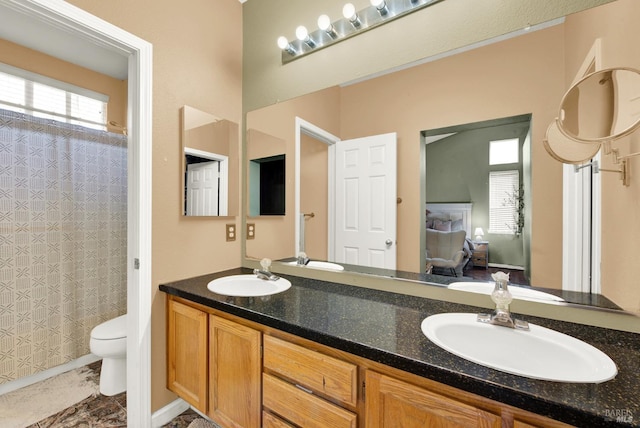 full bath featuring curtained shower, double vanity, toilet, and a sink