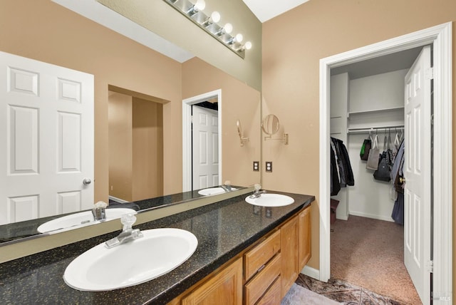 bathroom featuring double vanity, a spacious closet, and a sink