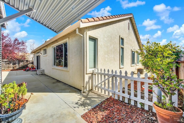 view of home's exterior with fence, a patio area, a tile roof, and stucco siding