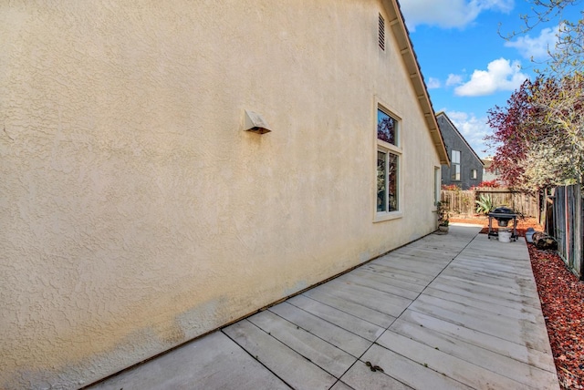 view of home's exterior featuring stucco siding, a wooden deck, and a fenced backyard