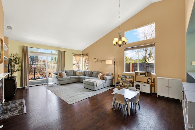 living area with a chandelier, dark wood finished floors, a wealth of natural light, and high vaulted ceiling