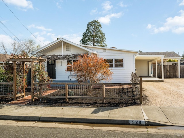 view of front of home featuring an attached carport, dirt driveway, and a fenced front yard