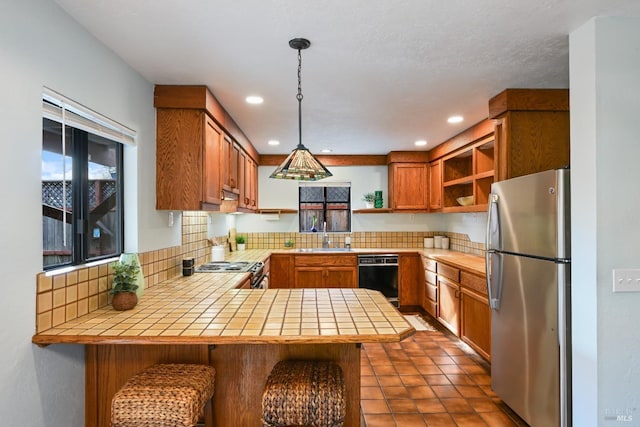 kitchen with open shelves, dishwasher, freestanding refrigerator, a peninsula, and tile counters