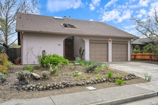 ranch-style home featuring concrete driveway, a garage, fence, and stucco siding