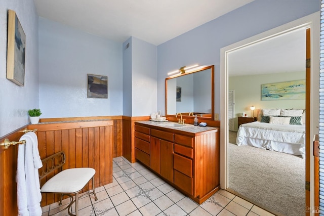 ensuite bathroom featuring a wainscoted wall, vanity, tile patterned floors, wooden walls, and ensuite bathroom