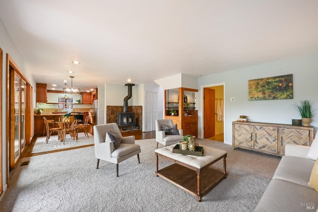 living area featuring a chandelier, carpet, and a wood stove