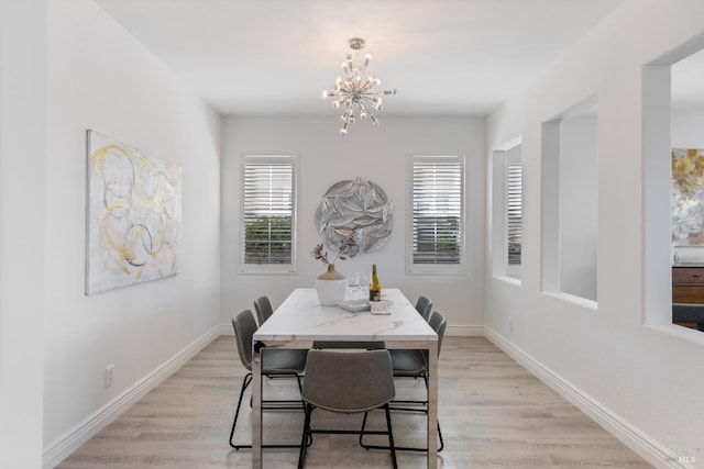 dining area featuring light wood-type flooring, baseboards, and a notable chandelier