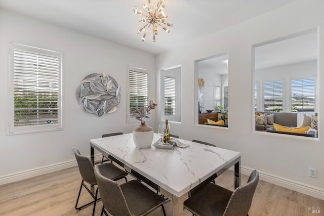 dining area with baseboards, a notable chandelier, light wood finished floors, and a healthy amount of sunlight