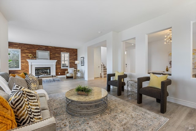 living room featuring plenty of natural light, light wood-style flooring, a chandelier, and stairway