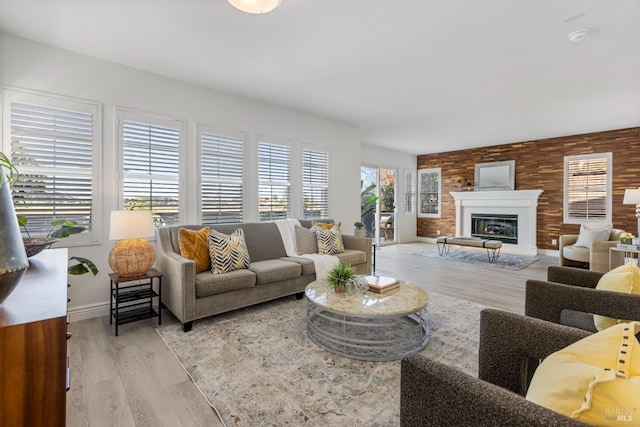 living area with a glass covered fireplace, wood finished floors, and baseboards
