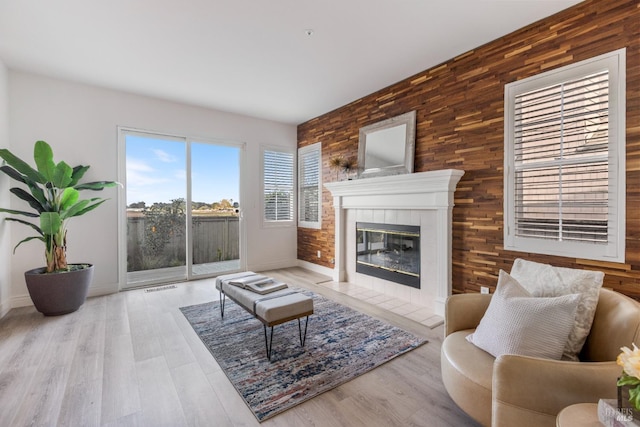 living room featuring a fireplace, an accent wall, wood walls, and baseboards