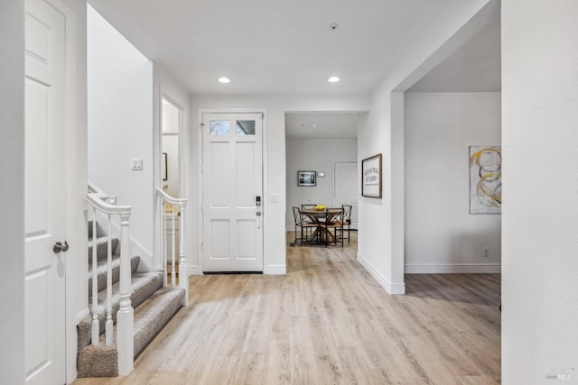foyer with light wood-type flooring, baseboards, recessed lighting, and stairway