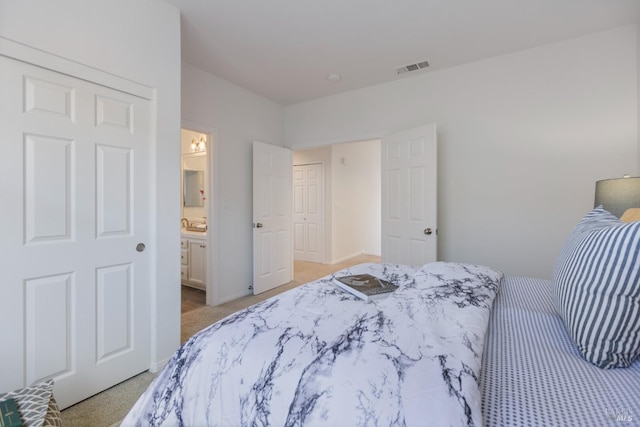 bedroom featuring light carpet, ensuite bath, and visible vents