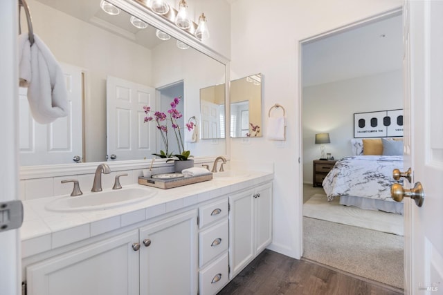 ensuite bathroom with double vanity, wood finished floors, ensuite bath, and a sink