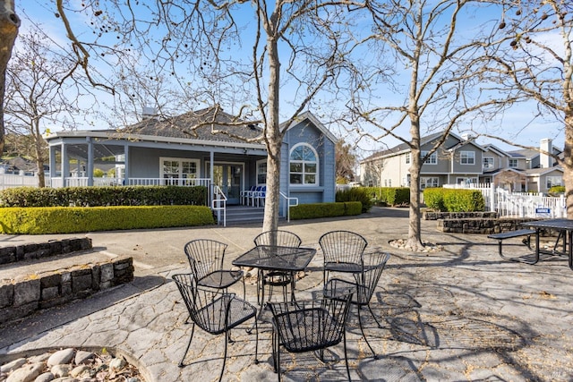 view of patio with fence, a residential view, and outdoor dining space