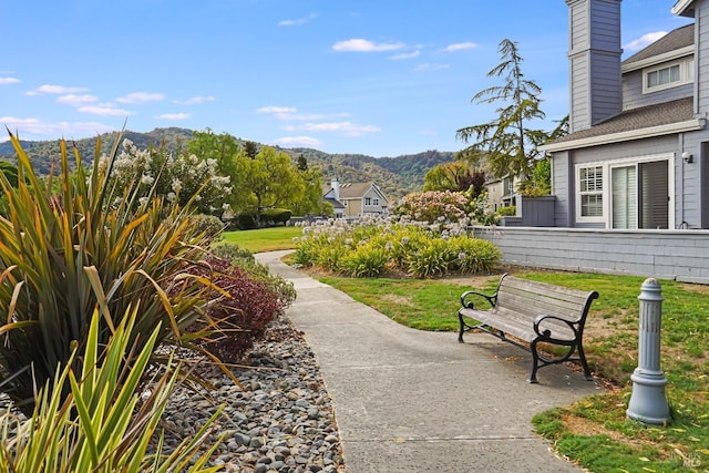 view of property's community featuring a patio area, a lawn, and a mountain view