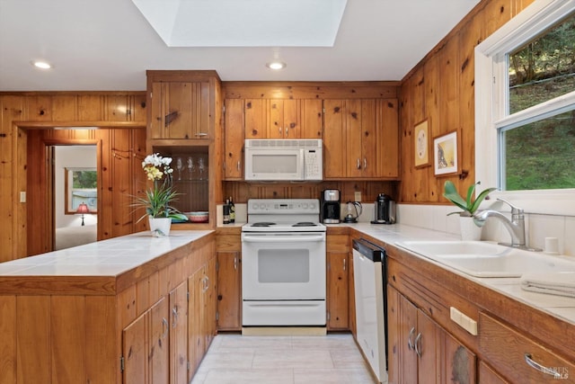 kitchen with white appliances, tile counters, a peninsula, and brown cabinets