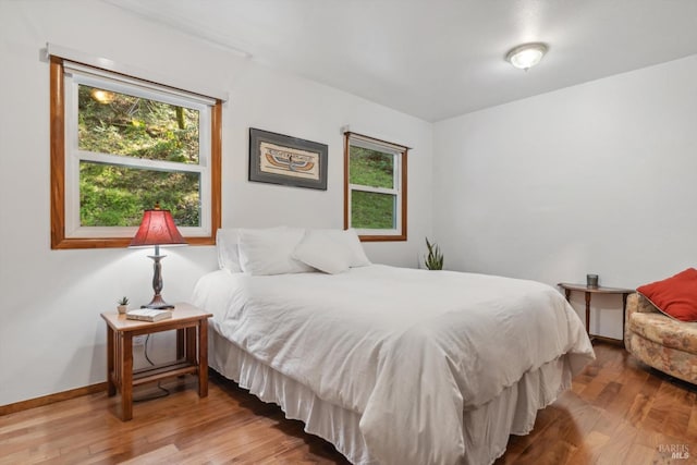 bedroom featuring multiple windows, baseboards, and wood finished floors