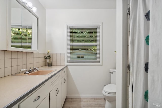 bathroom with plenty of natural light, toilet, vanity, and decorative backsplash