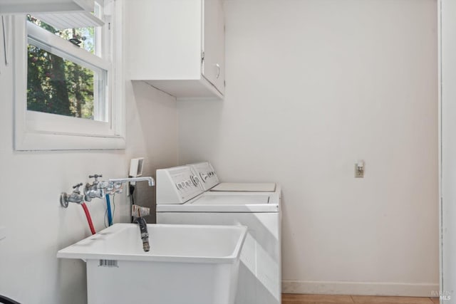 laundry room with a sink, cabinet space, baseboards, and washer and clothes dryer