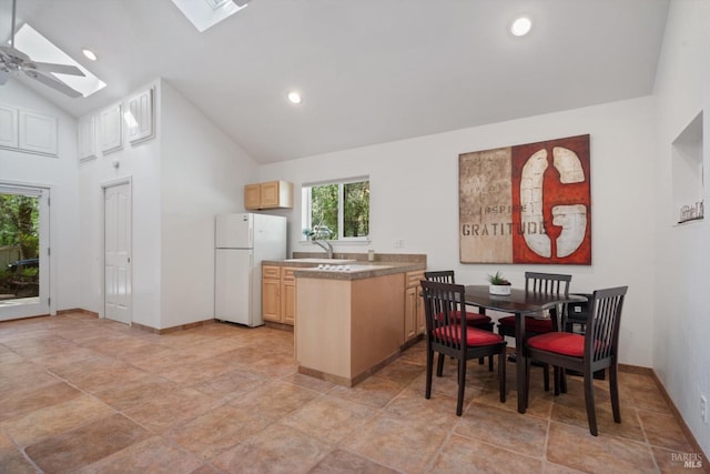 kitchen featuring light brown cabinets, a peninsula, a skylight, recessed lighting, and freestanding refrigerator